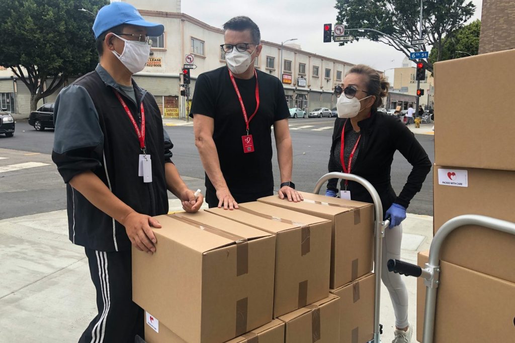 3 men in black polo shirt standing beside brown cardboard boxes
