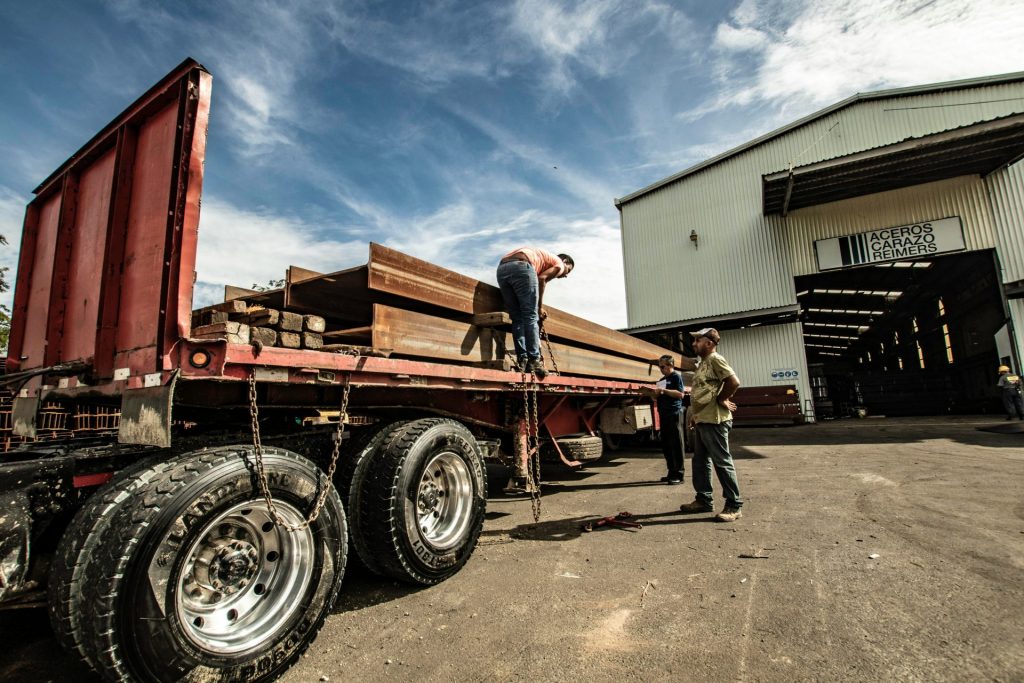 three men standing beside red vehicle trailer